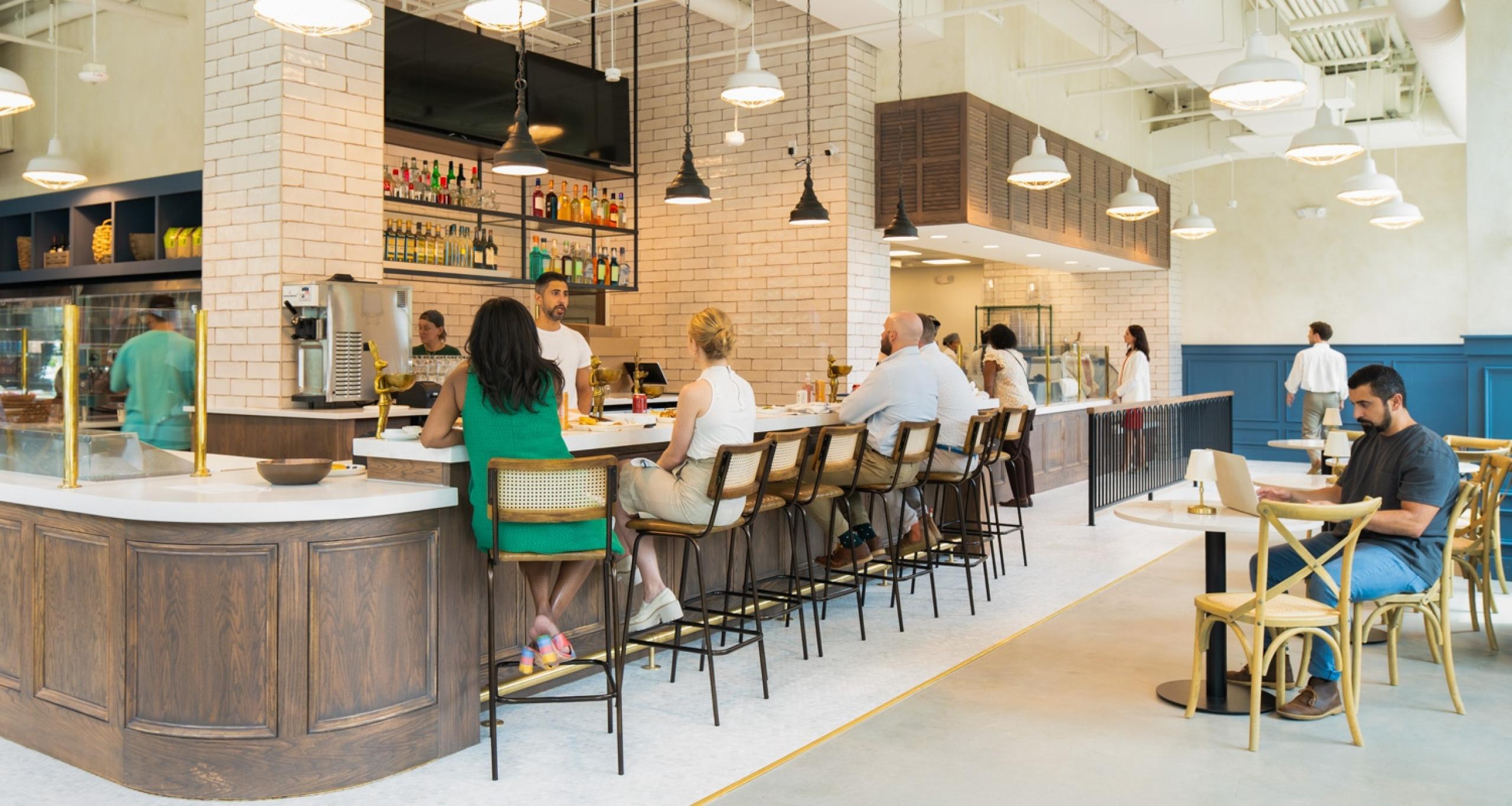 Customers sitting at a service counter and a table in Necessary Purveyor at Ponce City Market