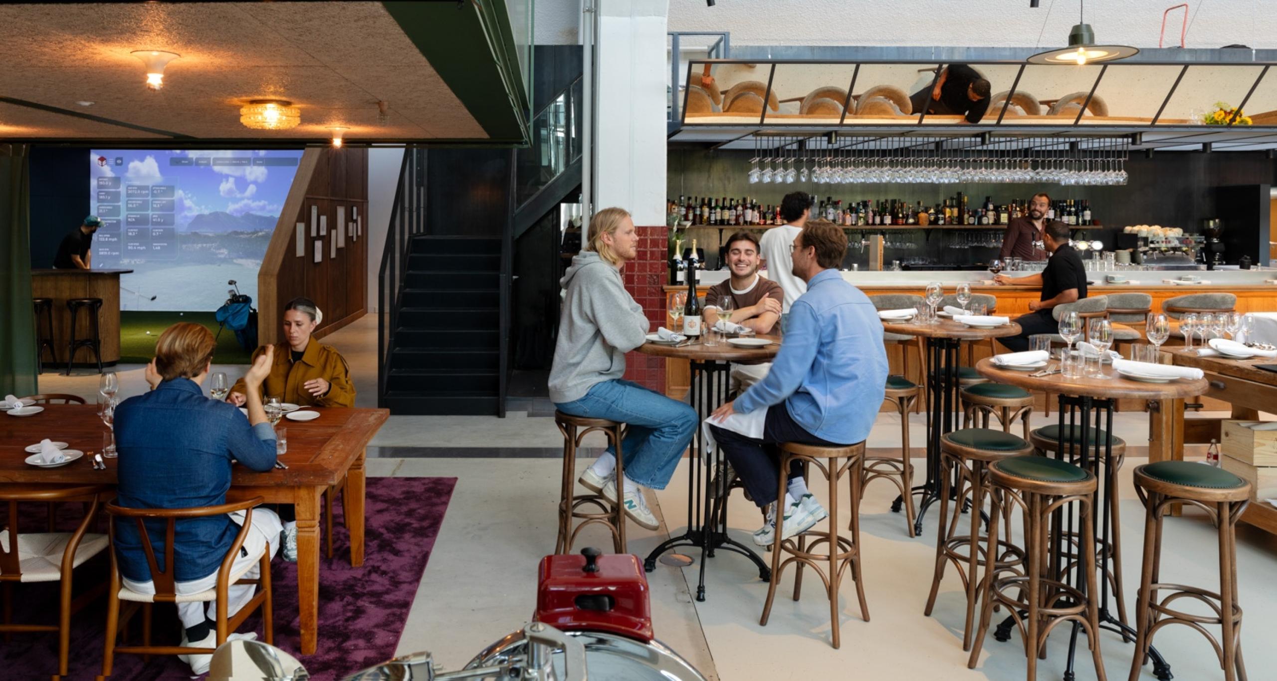 Customers sitting at tables inside Club Birdies at Schinkel District