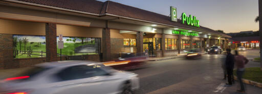 Country Club Plaza exterior of grocery store at dusk with cars and pedestrians in driveway